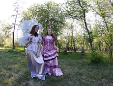 В парке усадьбы прогуливались барышни в платьях по моде 19 века.