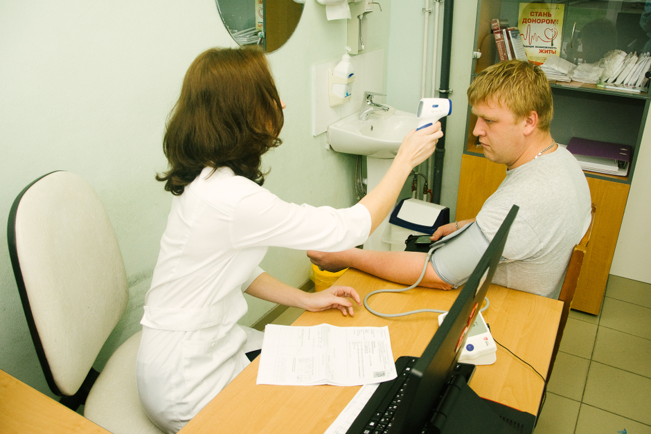 Врач измеряет температуру донора.