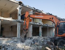 Здание демонтируют с помощью гидромолота. Он всё разбивает, затем крупные части крошат на мелкие фракции и вывозят.