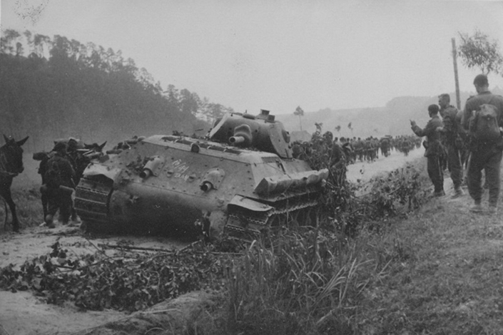 Немецкие солдаты проходят мимо брошенного советского танка Т-34