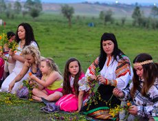 Собрав цветы, девушки рассаживаются вокруг шеста и под песни плетут венки.