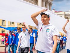 Сотни волонтеров выстроились в колонны и пронесли 50-метровое полотно российского триколора по улице Ленина до площади у памятника Александру Третьему.