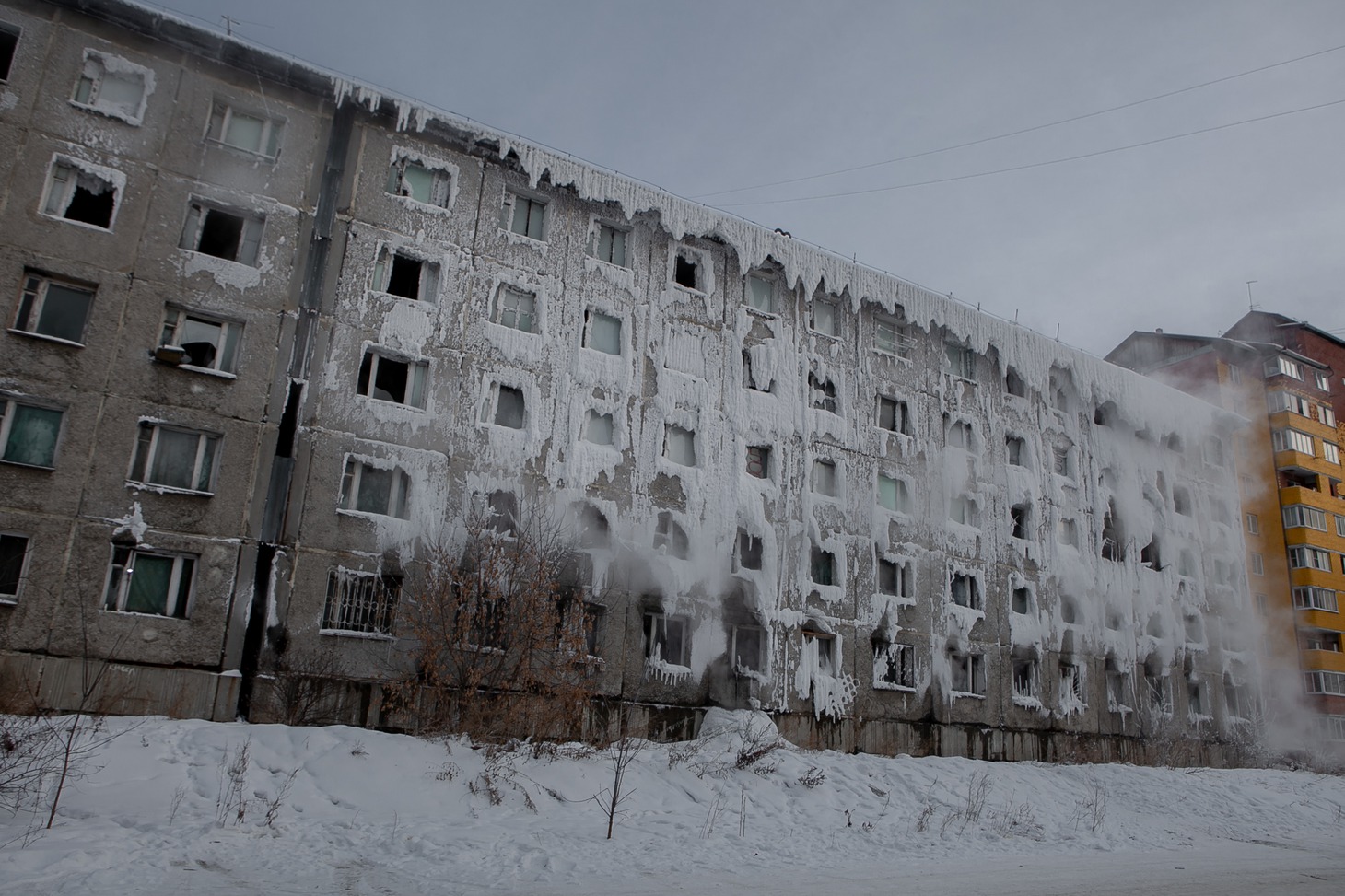 Одна часть здания ветхая, с разбитыми стеклами в оконных проемах, другая похожа на ледяную пещеру