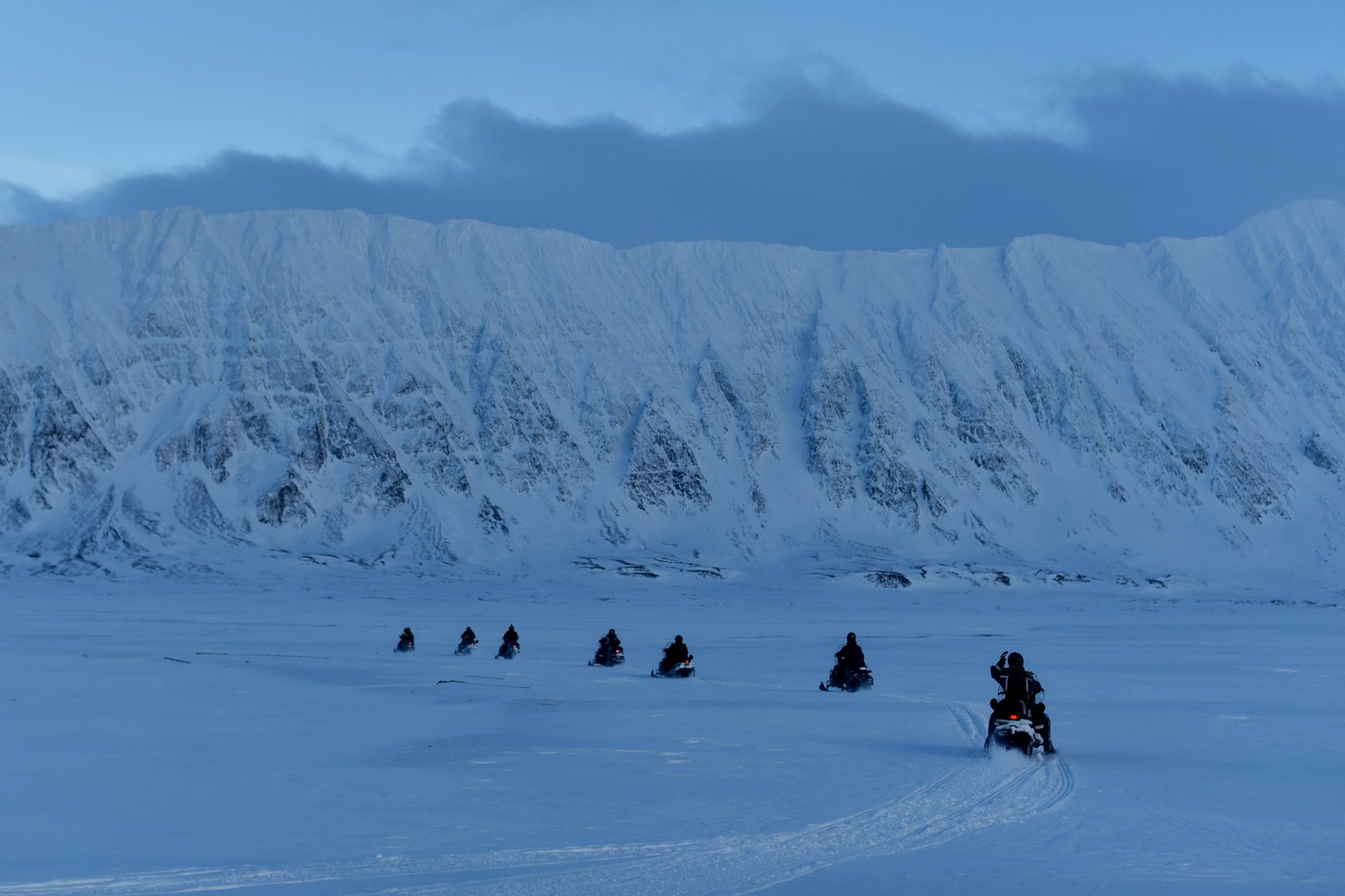 Колонна туристов в снегоходном туре, пересекают речную долину