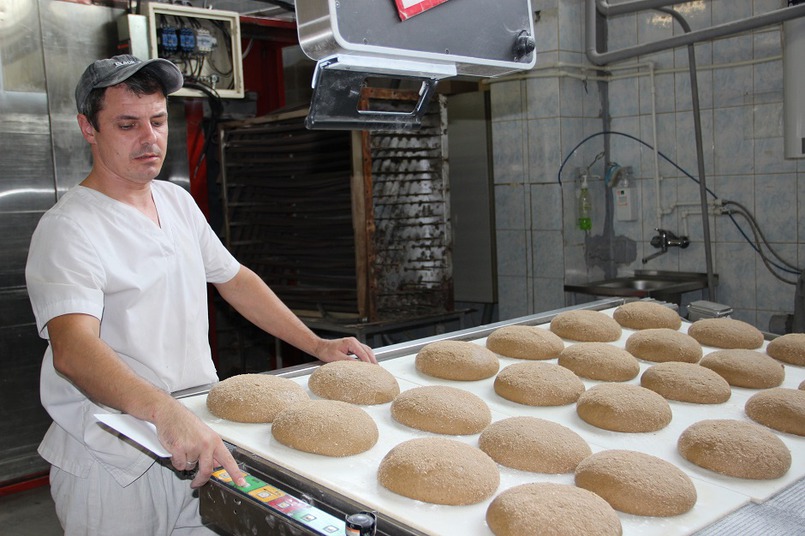 Пекарь-оператор включает автоматическую линию, и хлеба отправляются на передаточный стол