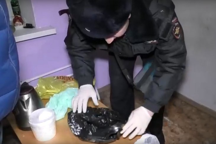 Полицейский осматривает вещи подозреваемого. Скриншот видео пресс-службы ГУ МВД России по Иркутской области